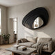Reflecta Black Wood Carving Mirror 3D Wall Art by Giant Sculptures displayed above a beige linen sofa in a neutral living room with concrete coffee table.