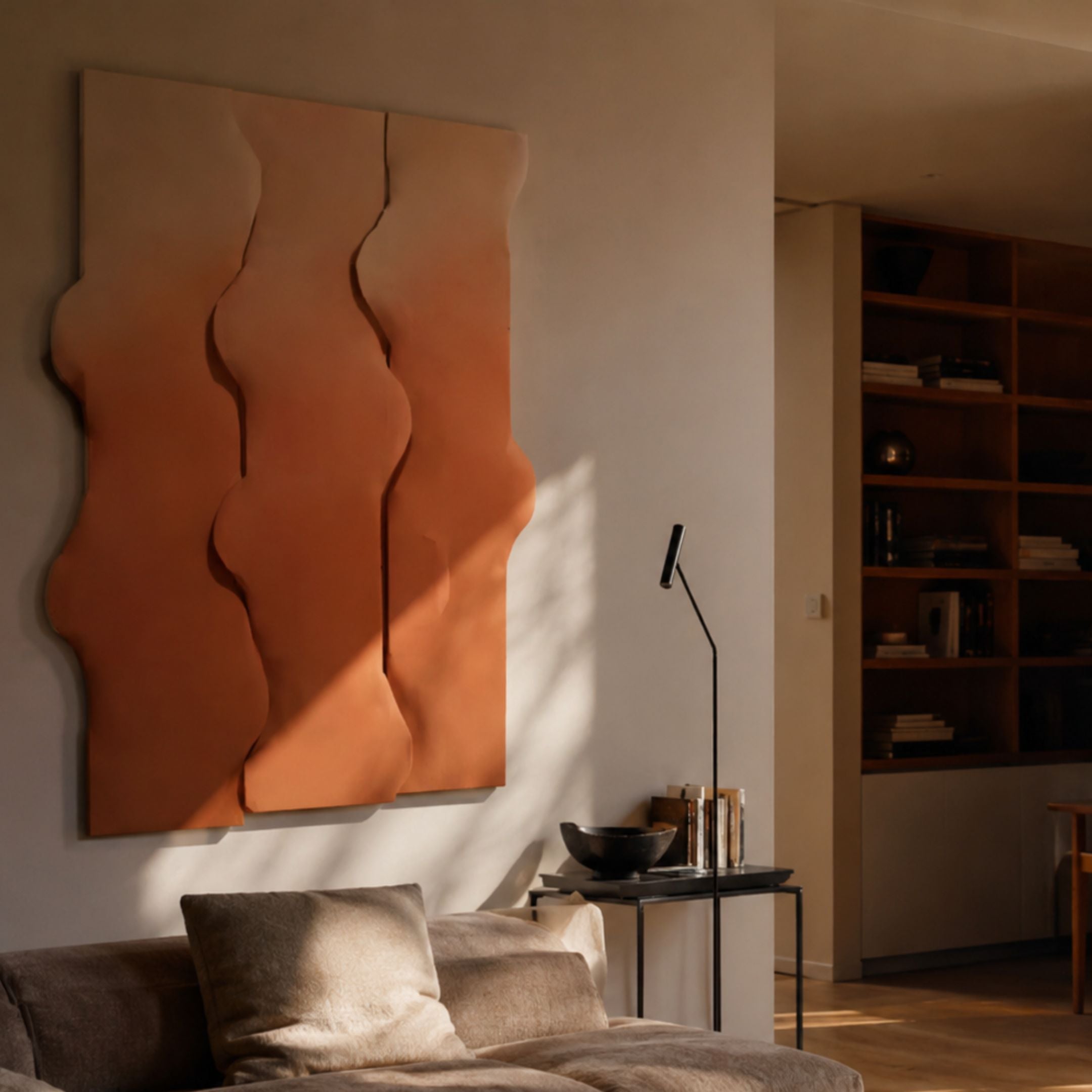 Mystique Orange Fabric Abstract Wood Relief 3D Wall Art mounted above a linen sofa in a warm living room, with a floor lamp and wooden bookshelf nearby.