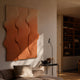 Mystique Orange Fabric Abstract Wood Relief 3D Wall Art mounted above a linen sofa in a warm living room, with a floor lamp and wooden bookshelf nearby.