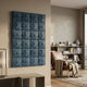 Vellura Blue Textured Wood Relief 3D Wall Art by Giant Sculptures mounted on a beige wall in a modern living room with a leather armchair and bookshelf.