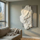 Veritas White & Grey Abstract Wood Relief 3D Wall Art by Giant Sculptures mounted on a grey living room wall above a linen sofa near a sunlit window.