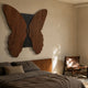 Lucerna Brown Butterfly Wood Carving 3D Wall Art mounted above a slatted-wood bed with brown linens, alongside a leather sling chair in a warm bedroom.