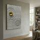 Calidora Golden Ripple Textured 3D Relief Wall Art by Giant Sculptures displayed on a pale wall in a modern living room with armchair and bookshelf.