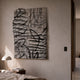 Calidora Abstract Contour Textured 3D Relief Wall Art by Giant Sculptures, a grey sculpted grid panel with black contour linework, mounted above a bedside table with a domed lamp in a neutral bedroom.