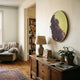 Auralune Verdant Rise Textured Abstract Round 3D Wall Art by Giant Sculptures hung above a wooden sideboard in a living room with an armchair and bookshelf nearby.