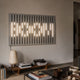 Verlux Linear Harmony 3D LED Wall Art by Giant Sculptures mounted above a low wooden bench with books and a ceramic lamp in a modern living room.