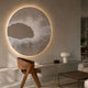 Earthlight Amber Glow 3D Textured Oil Painting LED Wall Art mounted above a concrete ledge in a neutral living room with a wooden chair and table lamp.
