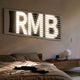 Aurova II Industrial Glow 3D LED Wall Art by Giant Sculptures, illuminated white RMB letters behind black horizontal slats, mounted above a bed in a neutral bedroom.