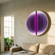 Onyx Sapphire Depth Acrylic 3D LED Wall Art by Giant Sculptures, a round piece with pink-purple gradient and concentric curves, mounted above a beige sofa.