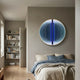 Onyx Orchid Bloom Acrylic 3D LED Wall Art mounted above a bed with blue and beige linens, glowing purple-blue beside a bookshelf in a modern bedroom.