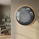 Genesis Glacier 3D Resin Crystal Porcelain LED Wall Art by Giant Sculptures, a backlit grey and white circular piece mounted beside a bookshelf and armchair.