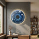 Genesis Azure 3D Resin Crystal Porcelain LED Wall Art with backlit blue iris design mounted above a wooden console with vase and books in a modern living room.