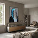 Elysian Veiled Grace 3D LED Wall Art by Giant Sculptures displayed above a wooden sideboard in a modern grey living room with armchair and bookshelf.