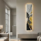 Floren Golden Veil Canvas LED Wall Art mounted vertically on a cream wall above a beige console, glowing warmly beside a modern living room with sofa and window.