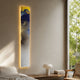 Chroma White Ethereal Glow LED Wall Art Canvas by Giant Sculptures, a tall vertical abstract in blue, gold, and white with backlit glow, mounted in a bedroom.
