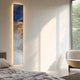 Chroma Blue Cloudlike Gradients LED Wall Art Canvas by Giant Sculptures, mounted vertically in a sunlit bedroom with warm LED back-glow, beside a cream boucle chair.