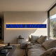 Textura 3D Sapphire Blue Leather Design Wall Art by Giant Sculptures, a long horizontal illuminated panel mounted above a beige sofa in a sunlit living room.