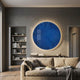 Lumea Vibrant Blue 3D LED Crystal Porcelain Wall Art by Giant Sculptures, a large circular deep-blue panel with backlit glow, mounted above a beige sofa in a modern living room.