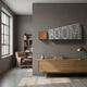 Illustra Bronze Highlight BOOM Text 3D Wooden Wall Art by Giant Sculptures mounted on a grey wall above an oak sideboard in a modern living room.