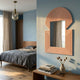 Aurellis Pink Arch & Square Geometric Mirror Frame Wall Art by Giant Sculptures mounted on a blue bedroom wall above a wooden console with books and a vase.