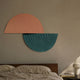 Orbitals Peach & Teal Semi-Circle Wood Carved Sandstone 3D Wall Art by Giant Sculptures displayed above a linen-dressed bed with wooden headboard.