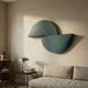 Orbitals Deep Teal Semi-Circle Wood Carved Sandstone 3D Wall Art with overlapping carved arcs displayed above a linen sofa, side table, and brass lamp.