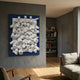 Axion White Wood Cluster & Sapphire Blue Edge 3D Wall Art by Giant Sculptures mounted on a grey wall in a modern living room beside a bookshelf and sofa.