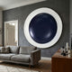 Aetherial Midnight Blue Glossy Circular Symmetry 3D Wall Art by Giant Sculptures mounted above a grey sofa on a dark grey wall in a modern living room.