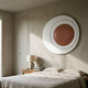 Aetherial Rosewood Glossy Circular Asymmetry 3D Wall Art by Giant Sculptures mounted above a wooden bedside table with lamp in a minimalist Nordic bedroom.