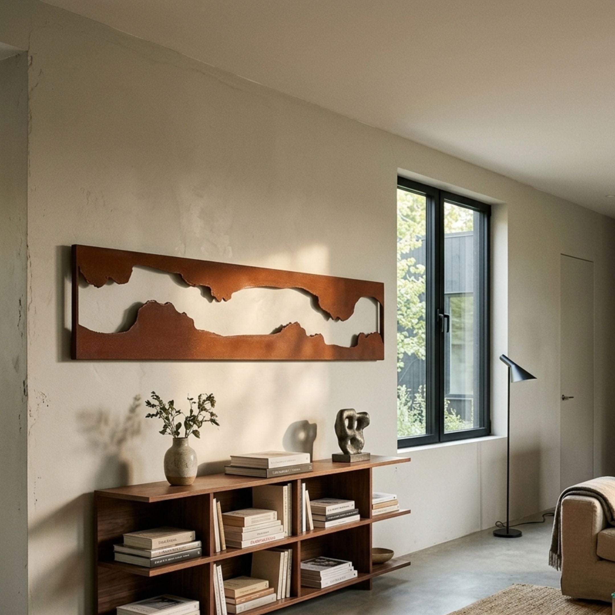 Stratara Rustic Brown Wood Carving Mirror Linear Wall Art by Giant Sculptures mounted above a walnut bookshelf in a sunlit living room with a window.