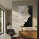 Stratura II Black & White Layered Paper Canvas Wall Art displayed above a wooden sideboard in a sunlit modern living room with a grey armchair.