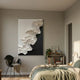 Stratura I Black & White Layered Paper Canvas Wall Art by Giant Sculptures displayed in a modern bedroom above a black chair, beside a bookshelf and bed.