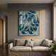 Filigree Ocean Waves Quilling Paper Wall Art in blue, teal, and white swirling layers, framed in black above a beige sofa in a grey-walled living room.