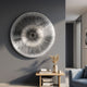 Oculis Warm Neutral Circular Handmade 3D Paper Wall Art by Giant Sculptures mounted on a grey wall above a wooden console with books, vase, and mug.