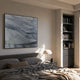 Terrane Tranquil Blue Layered Abstract Wall Art in a black frame above a grey upholstered bed, beside a dome lamp and built-in bookshelf.