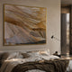 Terrane Timeless Beige Layered Abstract Wall Art in a gold frame above an upholstered bed with linen bedding, a floor lamp, and warm beige walls.