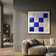 Geometrica Bold Blue & White Grid 3D Wood Relief Wall Art displayed above a beige linen sofa on a grey wall in a modern living room.