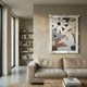 Florere Neutral Bloom Hand-Painted Sandstone 3D Wall Art by Giant Sculptures displayed above a linen sofa in a neutral living room with bookshelf nearby.