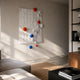 Orbison White Vertical 3D Wood Relief Wall Art with floating blue, orange, and white metal spheres displayed on a beige living room wall above a wooden sideboard.