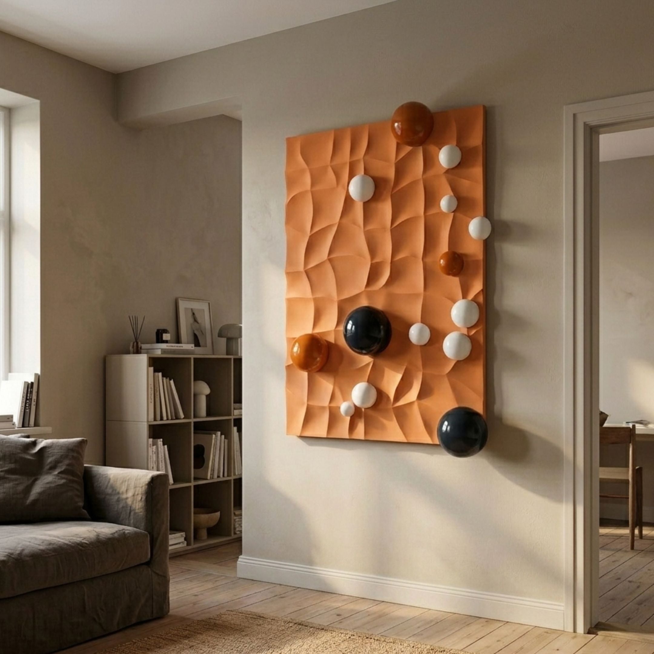 Orbison Terracotta 3D Wood Relief Wall Art with glossy blue, orange, and white metal spheres, mounted in a neutral living room beside a bookshelf and sofa.