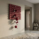 Orbina Crimson Red 3D Wood Relief Wall Art with red and silver metal spheres trailing down a neutral hallway wall beside a low bookshelf.
