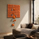 Orbina Orange 3D Wood Relief Wall Art With Metal Ball by Giant Sculptures mounted in a modern living room above a brown sofa with cream pillows.