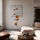 Orbina White 3D Wood Relief Wall Art with orange and white spheres cascading diagonally, displayed above a beige sofa in a sunlit living room.
