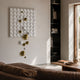 Orbina White 3D Wood Relief Wall Art by Giant Sculptures, with gold and white metal balls cascading from a grid panel, displayed in a sunlit living room.