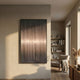 Celeste Cosmic Veil LED Wall Art by Giant Sculptures displayed on a beige plaster wall in a sunlit living space with a wooden bookshelf, armchair, and pampas grass.