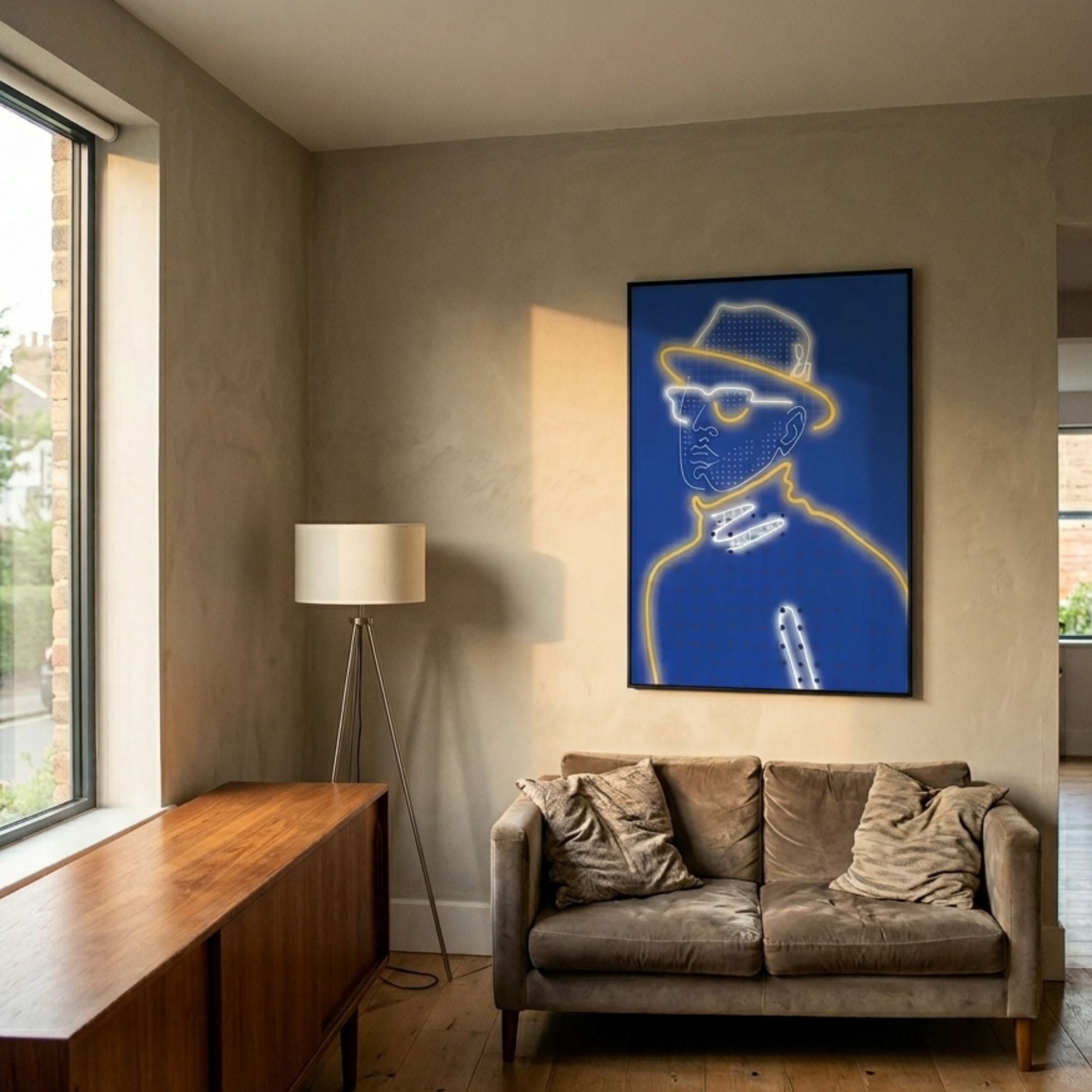Orison Blue Illusion Crystal Porcelain 3D LED Wall Art by Giant Sculptures, showing a neon-line portrait in yellow and white, displayed above a sofa beside a tripod lamp.