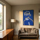 Orison Blue Illusion Crystal Porcelain 3D LED Wall Art by Giant Sculptures, showing a neon-line portrait in yellow and white, displayed above a sofa beside a tripod lamp.