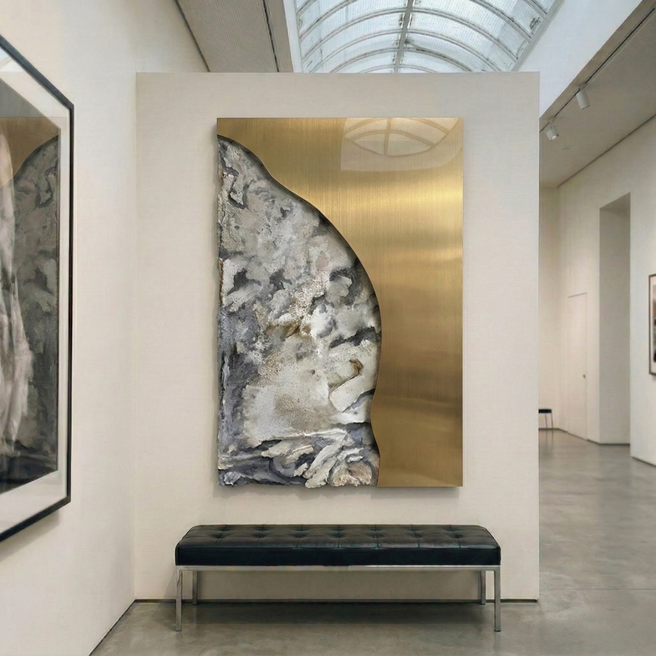 Gildrift Gold Steel & Stone Grey Curve Textured 3D Wall Art by Giant Sculptures displayed in a gallery setting with arched skylight, black leather bench below.