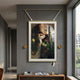 Aristo Balcony Romance Painting in gold frame by Giant Sculptures, displayed on a grey hallway wall above a wooden console with books and a lamp.