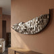 Arcana Metallic Earth Textured Mosaic Half-Moon 3D Wall Art mounted on a terracotta wall above a wooden sideboard in a warm contemporary living room.